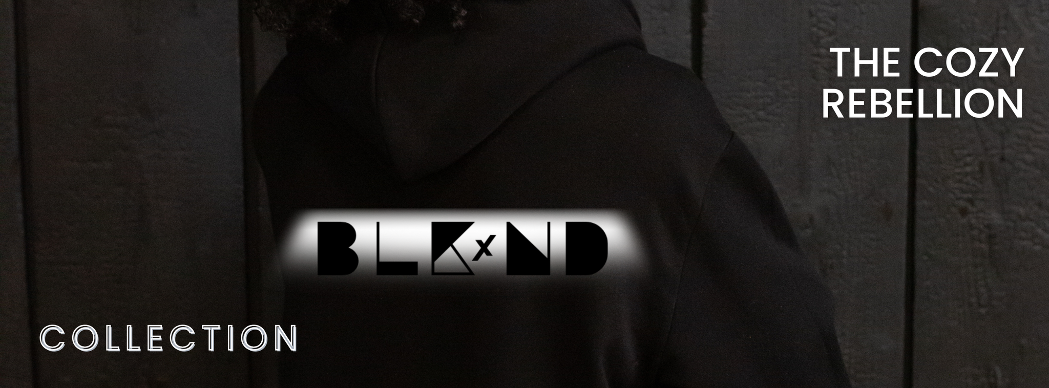 Person wearing a black hoodie with the BLKxND logo. Text reads “The Cozy Rebellion.” Collection banner for sensory-friendly graphic tees, hoodies, and sweatshirts.